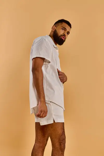 Um homem de camisa branca e calções fica confiante, mostrando o atletismo e a graça em sua postura equilibrada.. — Fotografia de Stock