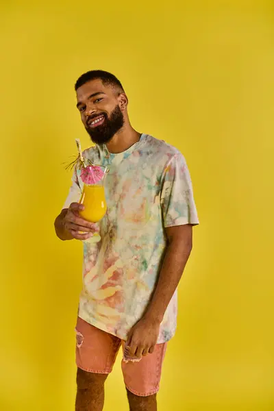 Ein stilvoller Mann im Krawattenfärberhemd hält einen Drink in der Hand und verleiht der Szene mit seinem lebendigen Outfit einen Farbtupfer. — Stockfoto
