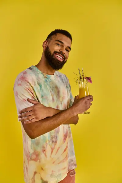 Um homem usando uma camisa vibrante de gravata é visto desfrutando de uma bebida. A camisa colorida adiciona um elemento lúdico à cena. — Fotografia de Stock