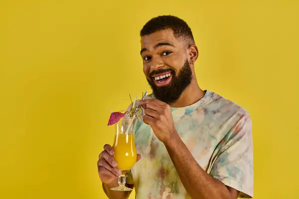 A man, with a serene expression, holds a glass of vivid orange juice, the condensation glistening on the glass. — Stock Photo