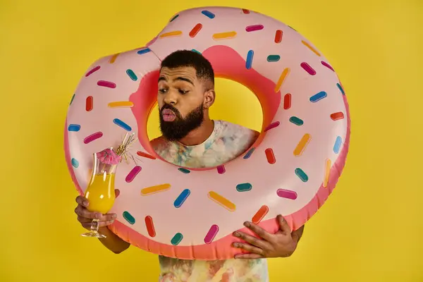 Ein Mann hält in der einen Hand einen riesigen Donut und in der anderen ein Glas Orangensaft und präsentiert ein köstliches Frühstück. — Stockfoto