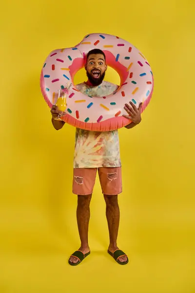 A man with a giant donut in one hand and a glass of beer in the other, enjoying the indulgent combination of sweet and savory flavors. — Stock Photo