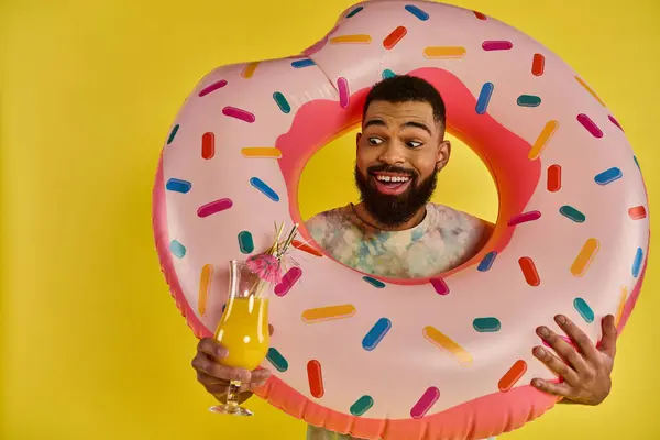Ein Mann hält freudig einen riesigen Donut und ein erfrischendes Getränk in der Hand und zeigt seine Liebe zu Leckereien und Entspannung. — Stockfoto