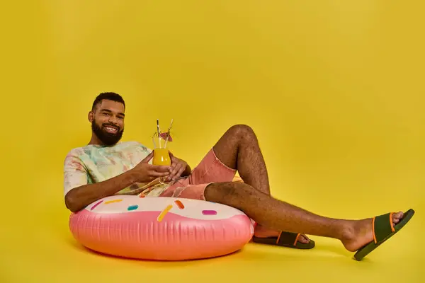 A man sitting serenely on top of a vibrant pink inflatable object, gazing into the distance with a peaceful expression on his face. — Stock Photo