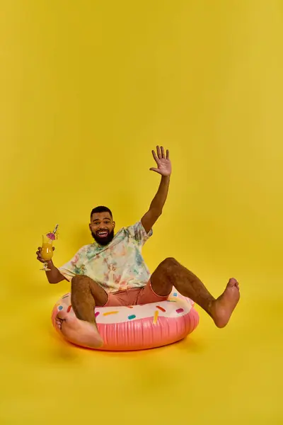 Ein Mann mit nachdenklichem Gesichtsausdruck sitzt auf einem bunten aufblasbaren Objekt und schwebt mühelos auf der Wasseroberfläche. — Stockfoto