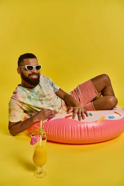 Um homem relaxa em um flutuador inflável, segurando uma bebida na mão, flutuando sem esforço em águas serenas sob o sol. — Fotografia de Stock