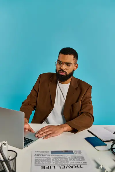 Un hombre está sentado en un escritorio, absorto en la pantalla de su computadora portátil. Sus dedos bailan a través del teclado, creando obras maestras digitales. - foto de stock