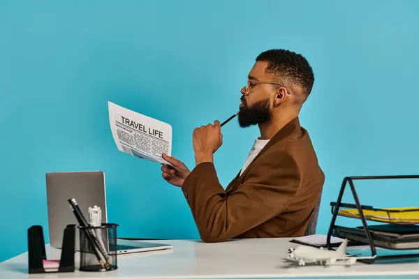 Un hombre sentado en un escritorio, absorto en leer un periódico. Su postura es enfocada y seria al absorber el contenido del documento. - foto de stock