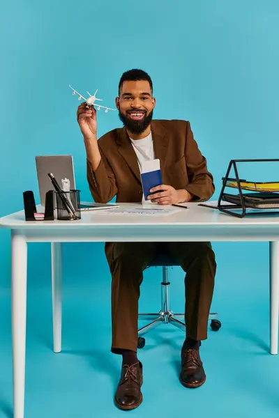 Um homem senta-se numa secretária, focado no ecrã do portátil. Ele está digitando e navegando, cercado por um espaço de trabalho cheio de papéis e material de escritório. — Fotografia de Stock