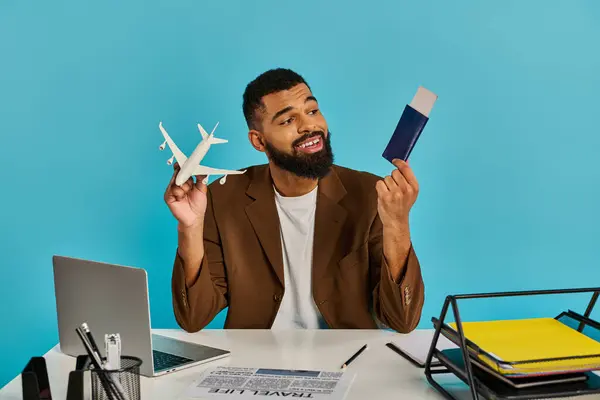 Un hombre está sentado en un escritorio, agarrando un pasaporte y billetes de avión, simbolizando la emoción y la anticipación de las próximas aventuras de viaje. - foto de stock