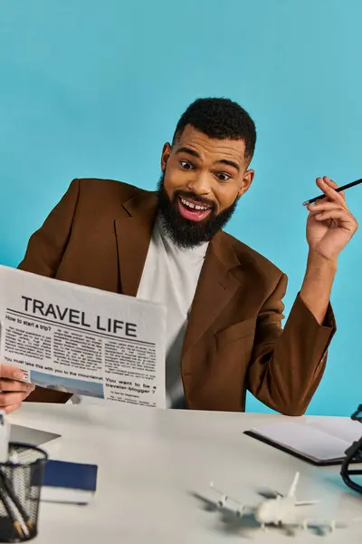 Человек с сосредоточенным выражением лица сидит за столом, держа в руках газету и читая последние новости и истории. — стоковое фото