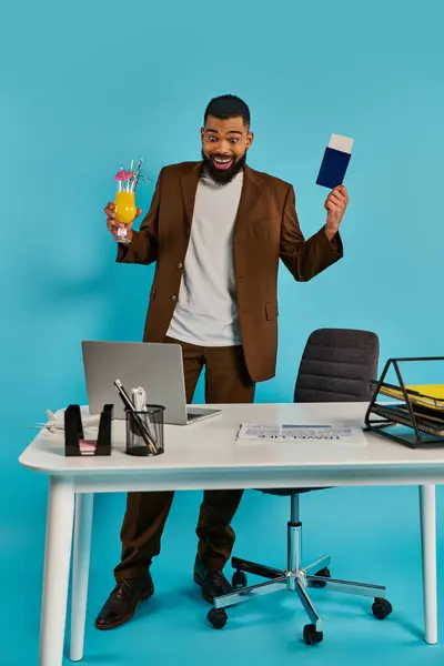 Un hombre con una expresión seria sentado en un escritorio, sosteniendo una tarjeta en una mano y escribiendo en un portátil con la otra mano. - foto de stock