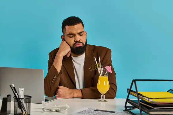 A man sits at a desk, intensely focused on his laptop screen, with a refreshing drink placed beside him. — Stock Photo