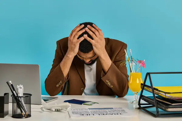 Un hombre sentado en un escritorio, sus manos acunando su cabeza en aparente angustia o profundo pensamiento, perdido en el momento. - foto de stock