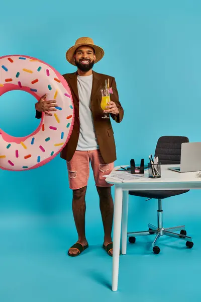 Ein Mann hält freudig einen riesigen Donut in der einen Hand und ein erfrischendes Getränk in der anderen und gönnt sich einen köstlichen und skurrilen Snack. — Stockfoto