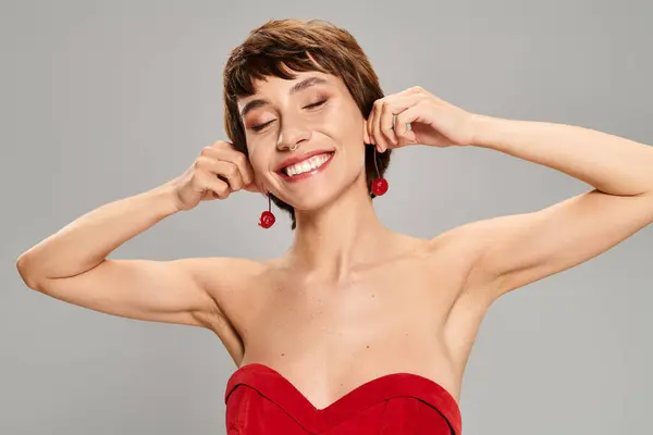 Una mujer encantadora con un vestido rojo sonríe. - foto de stock