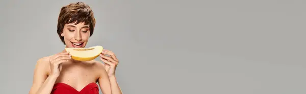 Junge Frau im roten Kleid schwelgt in Melone. — Stockfoto