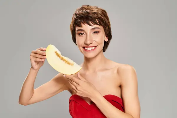 Una giovane donna in un abito rosso sorprendente posa con melone. — Foto stock