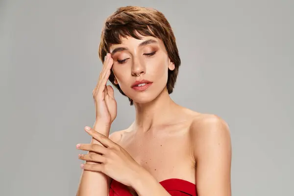 Mujer joven en vestido rojo, mano a cara. - foto de stock