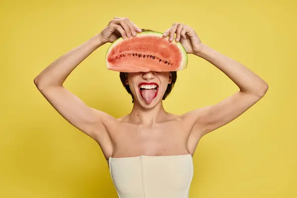 Uma jovem equilibra um pedaço de melancia na cabeça, cercada por cores vibrantes. — Fotografia de Stock
