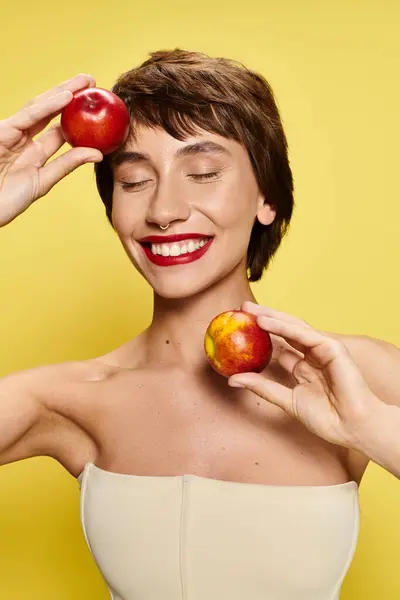 A young woman smiles while holding peaches. — Stock Photo