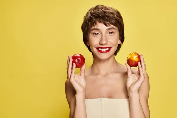Молодая женщина держит два персика с одним перед лицом. — стоковое фото