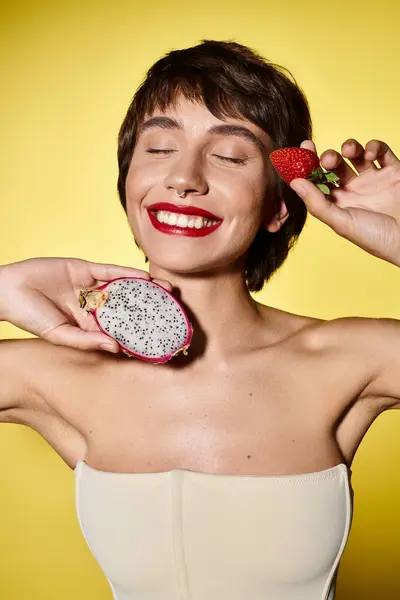 Young woman elegantly holds strawberry and dragon fruit. — Stock Photo