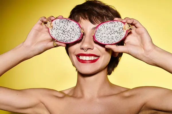 Mujer joven sosteniendo dos frutas delante de sus ojos. - foto de stock