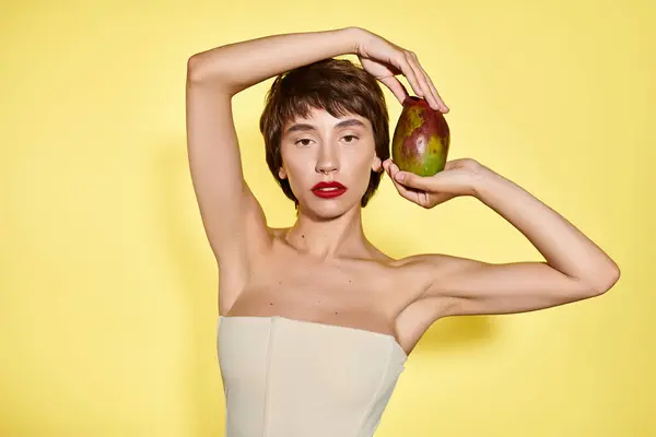 Una donna vestita di bianco regge con grazia il mango. — Foto stock