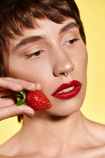 A young woman embraces a luscious strawberry against her cheek, radiating bliss. — Stock Photo