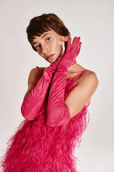 A fashionable young woman in a pink dress and gloves posing elegantly. — Stock Photo