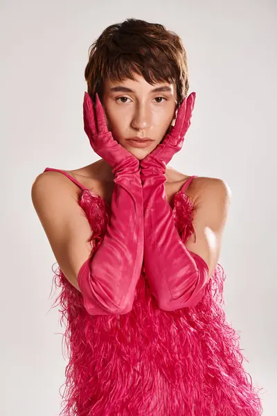 Elegante joven con guantes rosas y un vestido rosa en un vibrante telón de fondo. - foto de stock