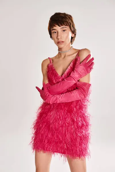 Una joven de moda posa en un vestido rosa y guantes a juego sobre un vibrante telón de fondo. - foto de stock