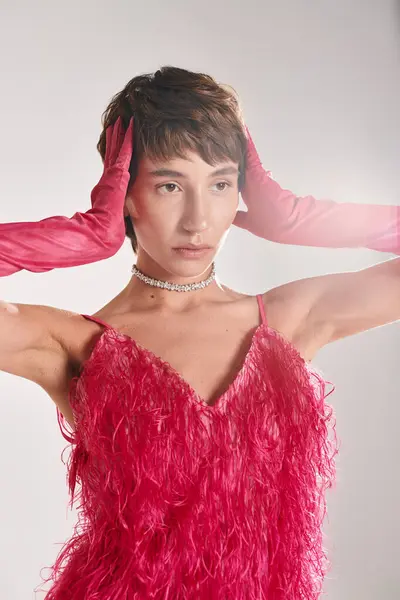 A woman in a red dress and pink gloves posing elegantly on a vibrant backdrop. — Stock Photo