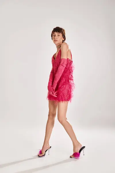 Giovane donna alla moda in un elegante abito rosa a piedi con grazia. — Foto stock
