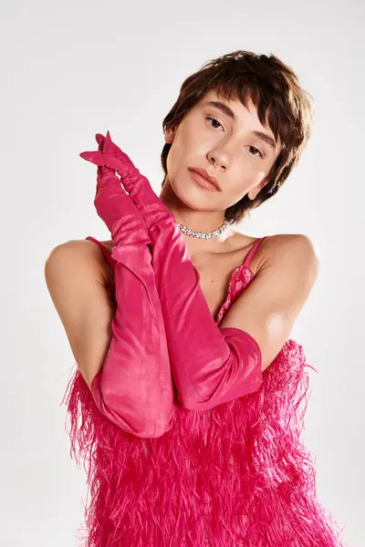 A fashionable young woman in a pink dress and gloves posing gracefully. — Stock Photo