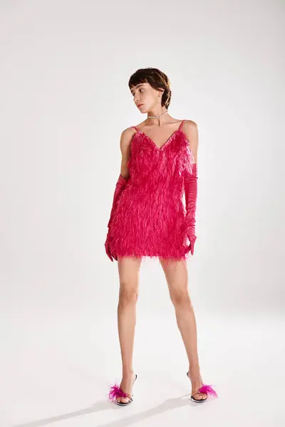 Fashionable young woman posing in elegant pink feather dress against vibrant backdrop. — Stock Photo
