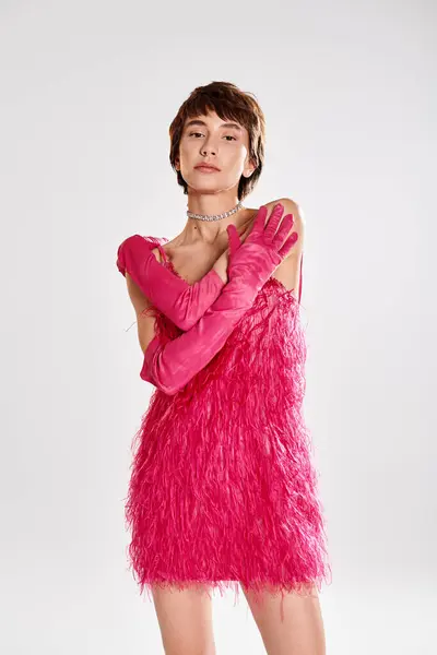 La mujer a la moda toca la pose en el vestido rosado y los guantes sobre el telón de fondo vibrante. - foto de stock