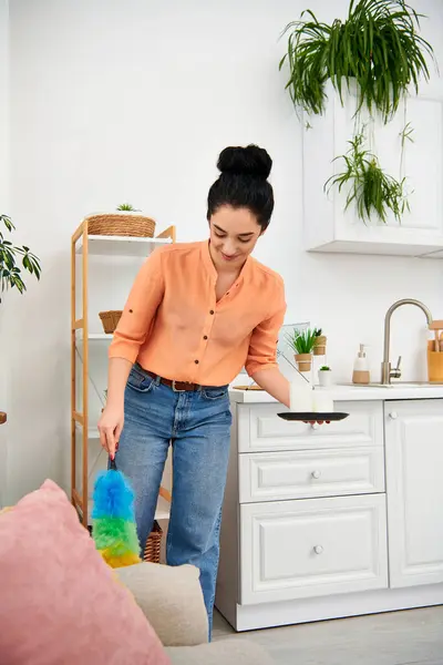 A stylish woman in casual attire diligently wipes down her kitchen with a rag, creating a bright and sparkling space. — Stock Photo