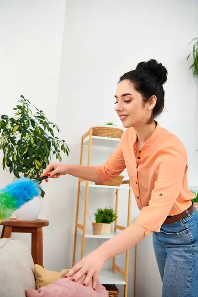 Una mujer con atuendo casual juega alegremente con un animal de peluche, aportando un toque de fantasía a su rutina de limpieza.. - foto de stock