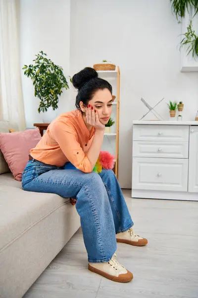 A chic, casually dressed woman sits on a couch, engrossed in a cell phone conversation. — Stock Photo