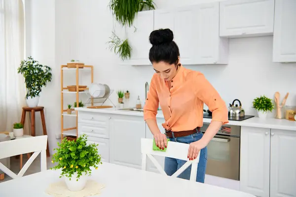 A stylish woman in casual attire stands in the kitchen, skillfully cutting a piece of paper with precision and creativity. — Stock Photo