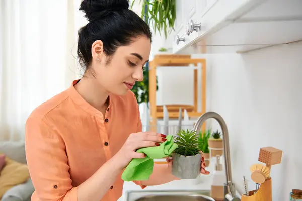 A stylish woman holding a potted plant in a cozy kitchen setting. — Stock Photo