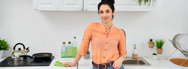 Una mujer elegante con atuendo casual sostiene con confianza una sartén en la cocina. - foto de stock