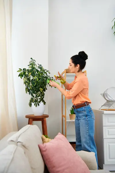 Una mujer con estilo se encuentra en su sala de estar junto a una planta en maceta vibrante, añadiendo un toque de naturaleza a su espacio. - foto de stock