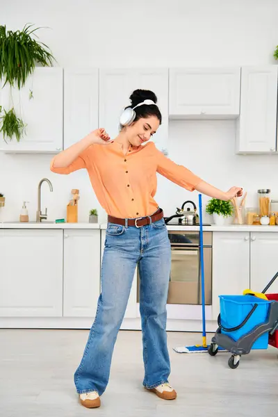 A stylish woman in casual attire energetically mopping the floor, with focus and determination. — Stock Photo
