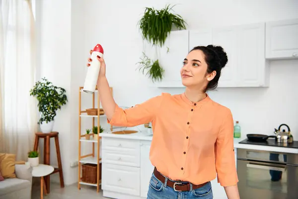 A stylish woman in casual attire holding a red and white object, possibly cleaning her home. — Stock Photo