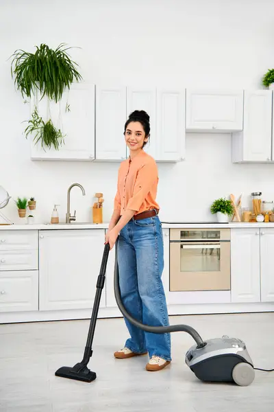 A stylish woman in casual attire gracefully vacuums the floor of her home. — Stock Photo