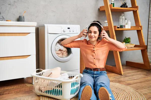 Eine stilvolle Frau sitzt neben einer Waschmaschine und macht eine Pause beim Putzen ihres Hauses. — Stockfoto