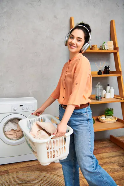 Une femme élégante tenant un panier de poulets debout devant une machine à laver à la maison. — Photo de stock